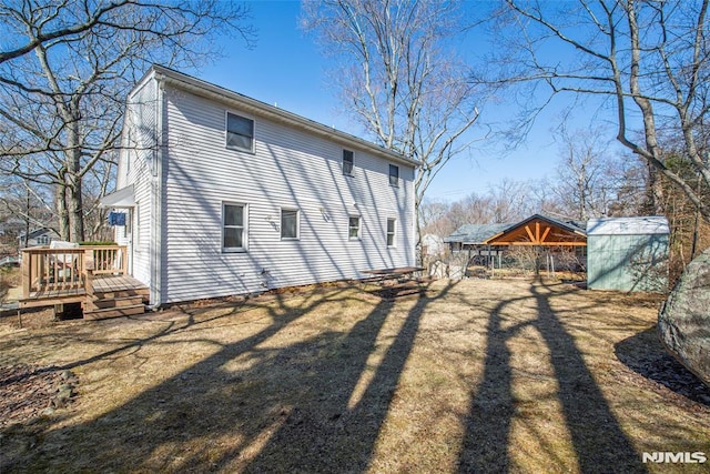 rear view of property with an outbuilding, a wooden deck, and a yard