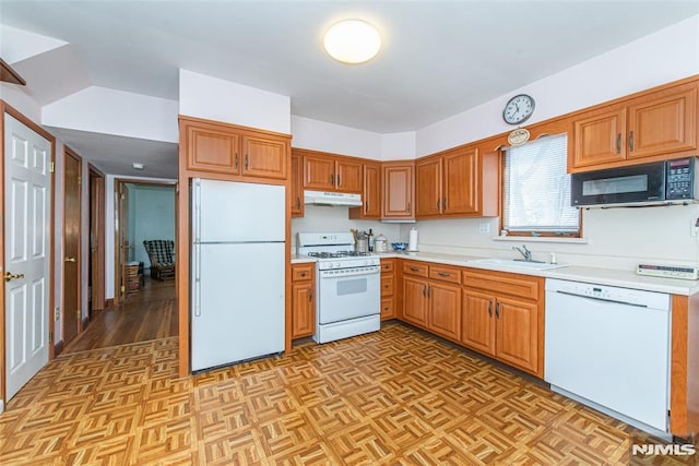 kitchen with under cabinet range hood, white appliances, light countertops, and a sink