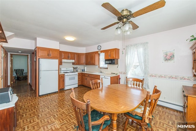 dining area with a baseboard heating unit, a ceiling fan, and a wainscoted wall