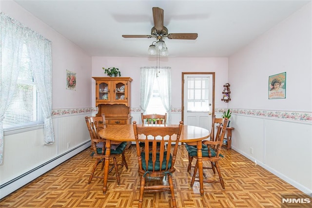 dining room featuring a wainscoted wall, baseboard heating, and a ceiling fan