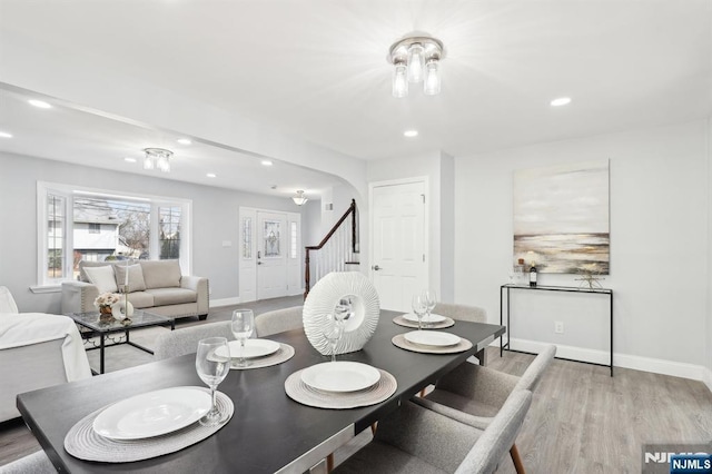 dining space featuring arched walkways, recessed lighting, light wood-type flooring, and baseboards