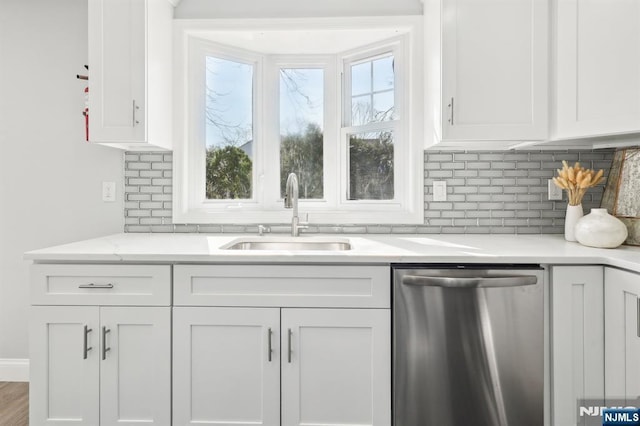 kitchen featuring stainless steel dishwasher, tasteful backsplash, white cabinetry, and a sink