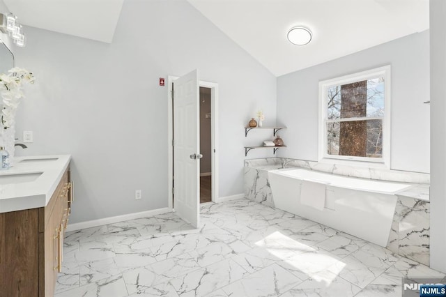 bathroom with a bath, marble finish floor, baseboards, and double vanity