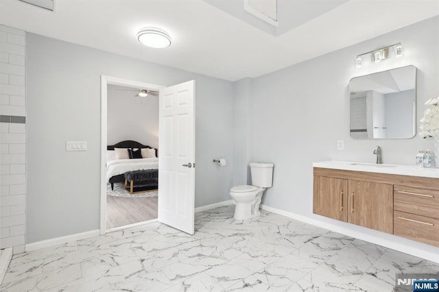 ensuite bathroom with toilet, marble finish floor, ensuite bath, baseboards, and vanity