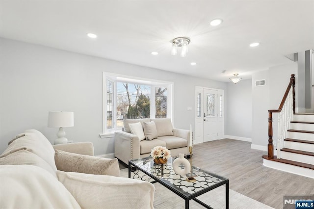 living room featuring visible vents, baseboards, stairs, recessed lighting, and light wood-style floors