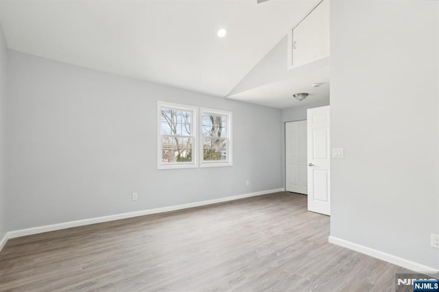 empty room with recessed lighting, light wood-style floors, baseboards, and high vaulted ceiling