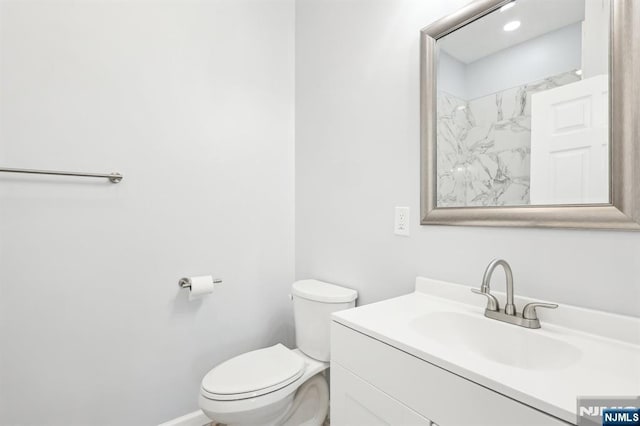 bathroom featuring toilet, vanity, and baseboards