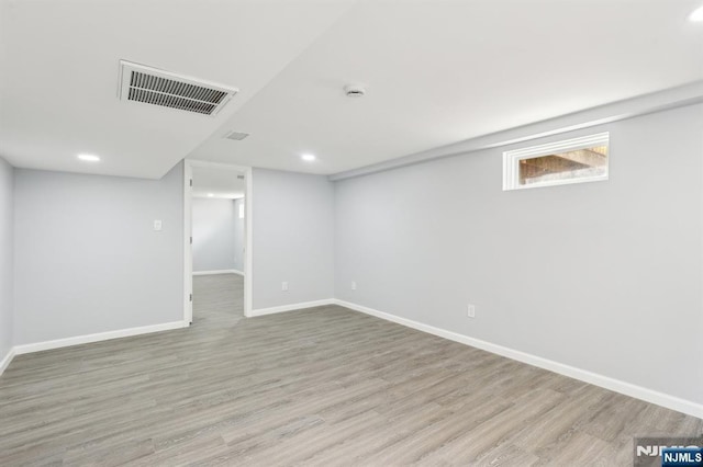 basement featuring visible vents, baseboards, and light wood-style floors