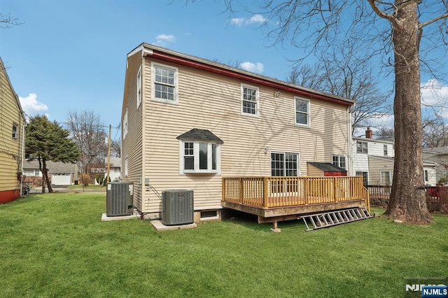 rear view of house with central AC unit, a lawn, and a wooden deck