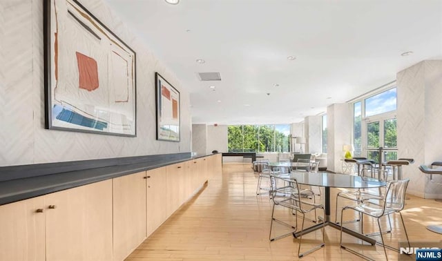 dining room with light wood-type flooring, expansive windows, and a wealth of natural light