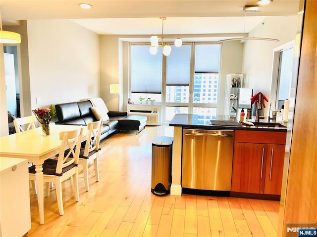 kitchen with open floor plan, light wood-type flooring, dishwasher, brown cabinetry, and dark countertops