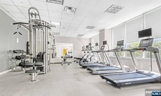 exercise room with a paneled ceiling, visible vents, and baseboards