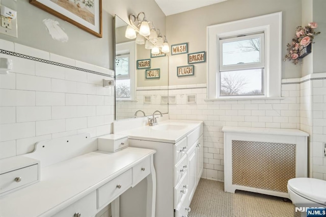 bathroom featuring vanity, radiator, wainscoting, tile walls, and tile patterned floors