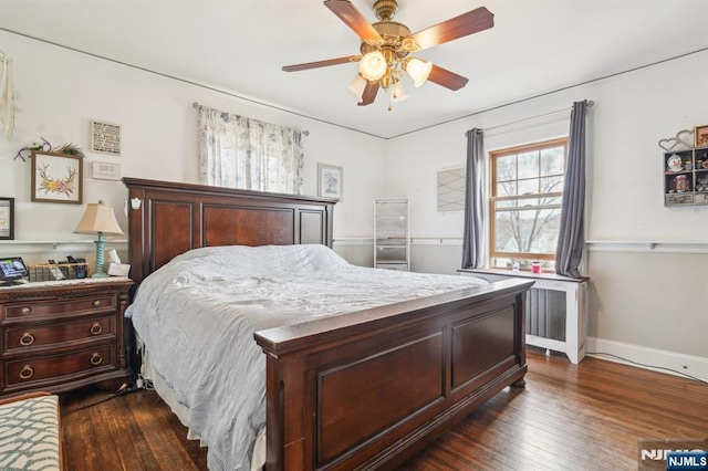 bedroom featuring ceiling fan, baseboards, dark wood-style floors, and radiator heating unit