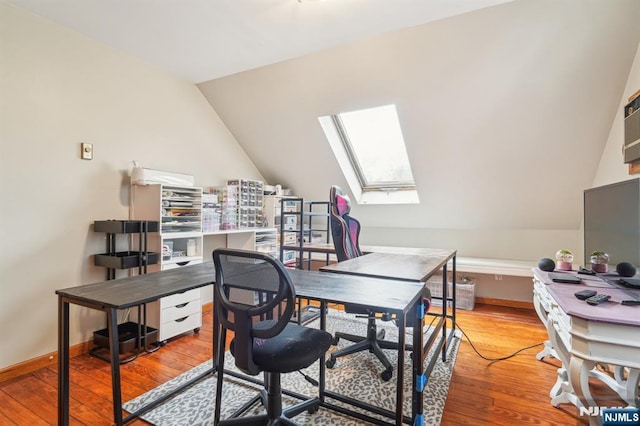 home office featuring baseboards, lofted ceiling with skylight, and hardwood / wood-style flooring