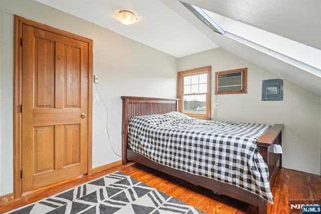 bedroom with lofted ceiling with skylight, wood finished floors, baseboards, and a wall mounted air conditioner