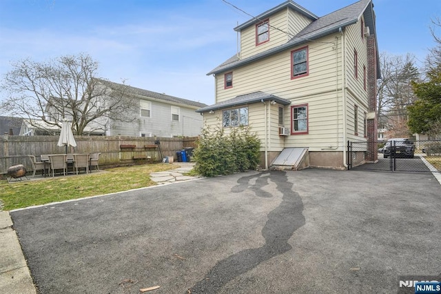 back of property featuring a gate, fence, and a lawn