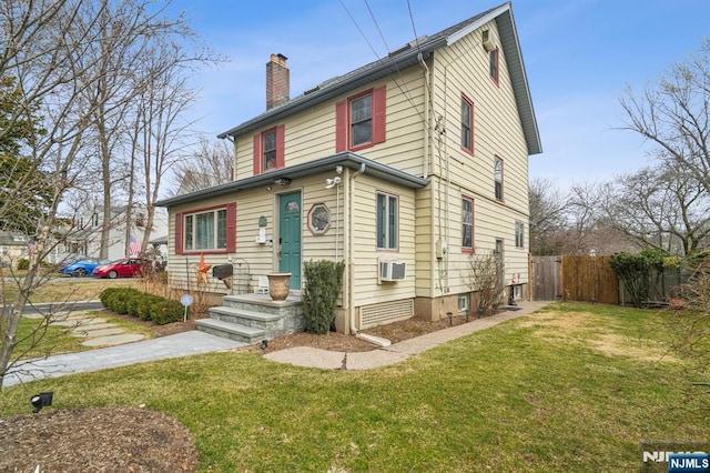 view of front facade with an AC wall unit, a chimney, a front yard, and fence