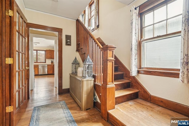 stairs with ornamental molding, baseboards, and wood finished floors