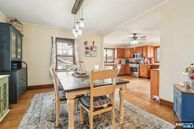 dining space with a ceiling fan, light wood-style floors, baseboards, and ornamental molding