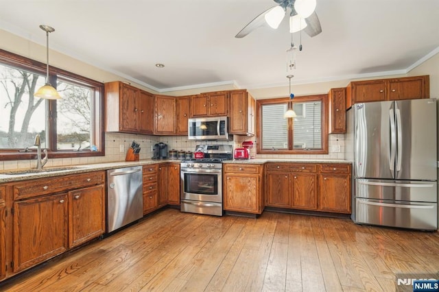 kitchen with a sink, stainless steel appliances, brown cabinets, and light wood finished floors