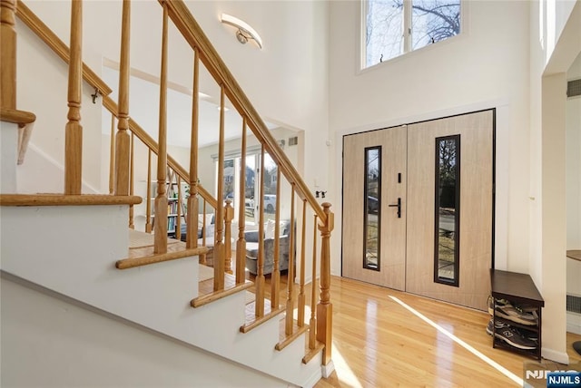 foyer entrance with stairway, a high ceiling, and wood finished floors