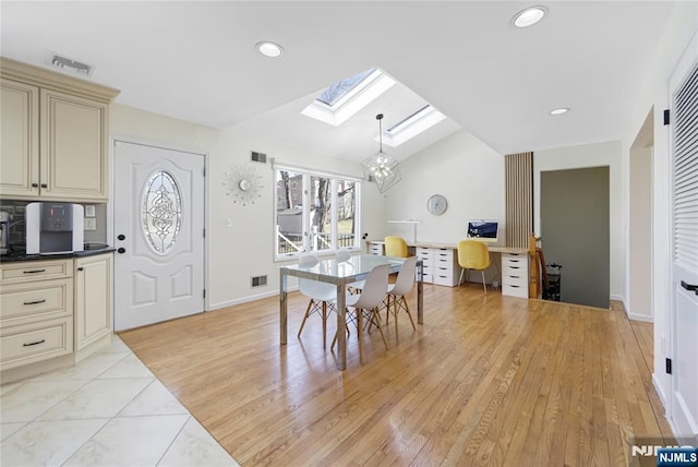 dining room with lofted ceiling with skylight, light wood-style floors, visible vents, and a notable chandelier