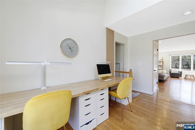 office featuring light wood-style floors, baseboards, and built in desk