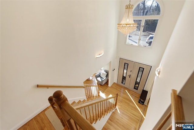 foyer featuring a notable chandelier, a high ceiling, baseboards, light wood-style floors, and stairway