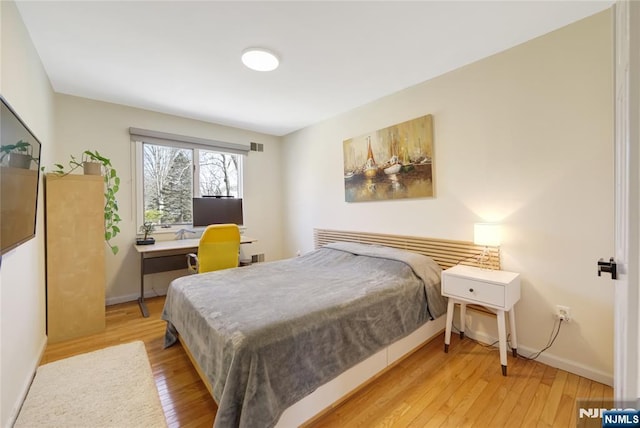 bedroom with visible vents, baseboards, and hardwood / wood-style flooring