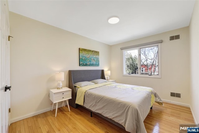 bedroom featuring baseboards, visible vents, and light wood finished floors