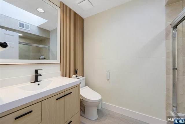 bathroom featuring a tile shower, visible vents, vanity, and toilet