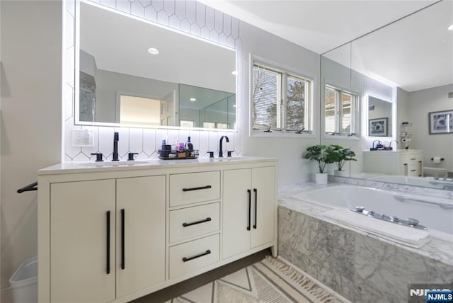 bathroom with double vanity, a sink, and a bath