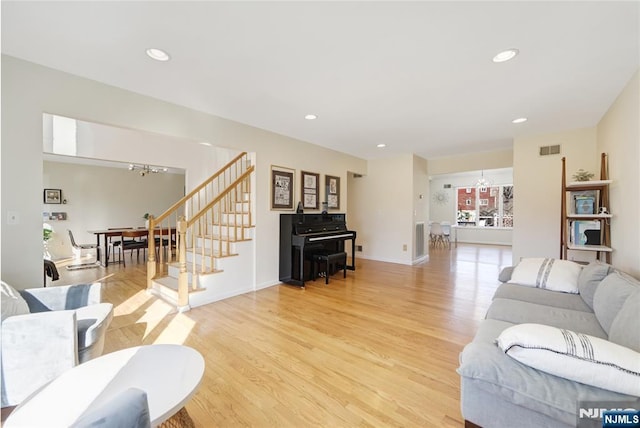 living room with light wood finished floors, recessed lighting, visible vents, a chandelier, and stairs