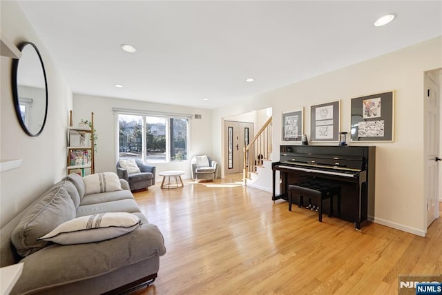 living area featuring light wood-type flooring, stairway, baseboards, and recessed lighting