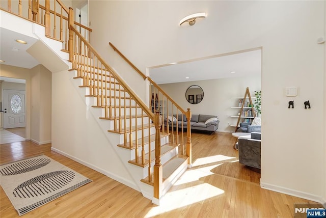 staircase featuring a high ceiling, baseboards, and wood finished floors