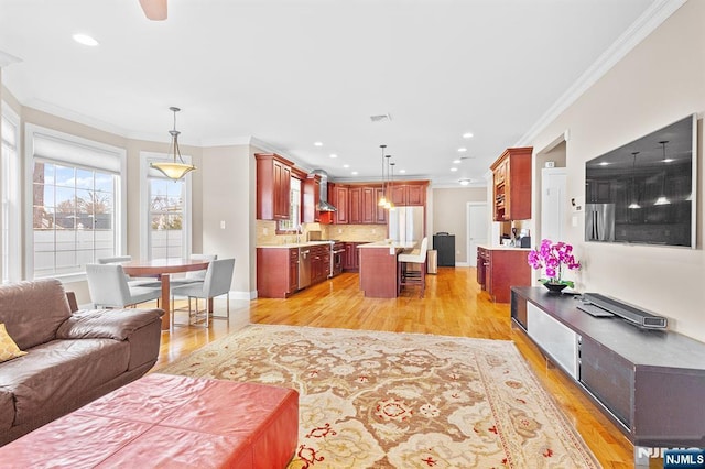 living area with baseboards, visible vents, light wood-style flooring, recessed lighting, and crown molding