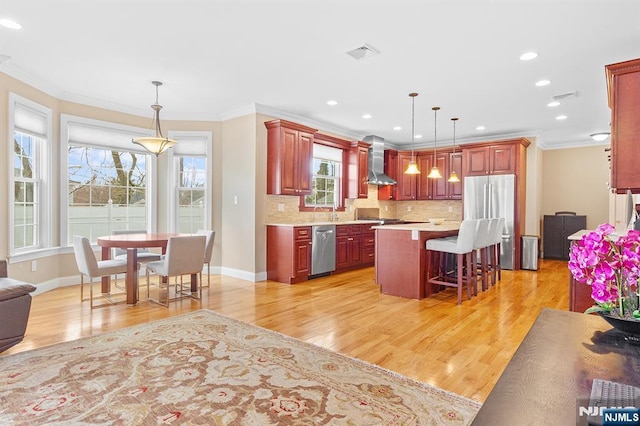 kitchen featuring tasteful backsplash, visible vents, light countertops, appliances with stainless steel finishes, and wall chimney exhaust hood