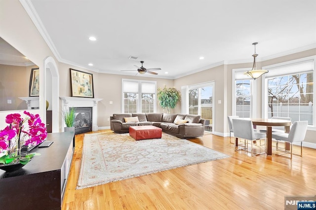 living room with visible vents, crown molding, recessed lighting, wood finished floors, and a glass covered fireplace