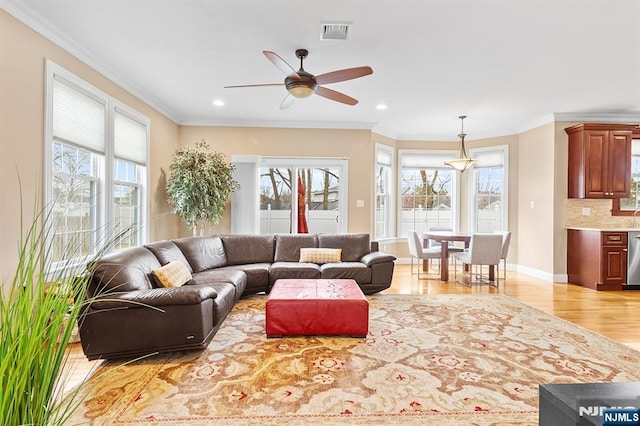 living area featuring visible vents, light wood-style flooring, a ceiling fan, recessed lighting, and crown molding