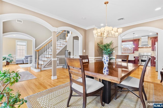 dining space featuring stairway, visible vents, light wood finished floors, and ornamental molding