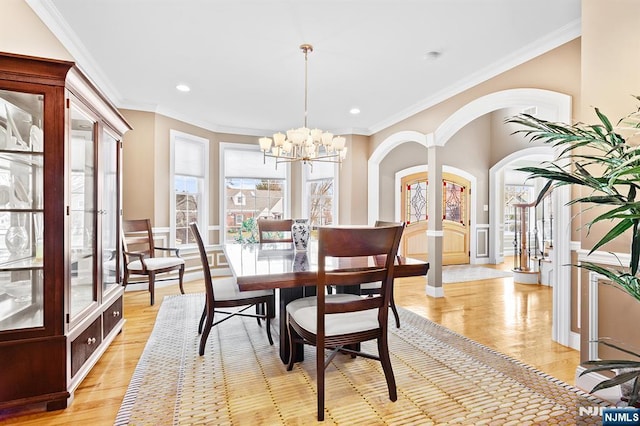 dining area with stairs, an inviting chandelier, crown molding, and arched walkways