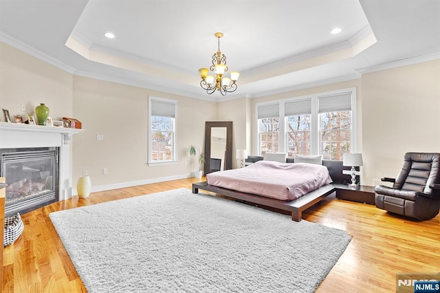 bedroom with baseboards, light wood-type flooring, a raised ceiling, and an inviting chandelier