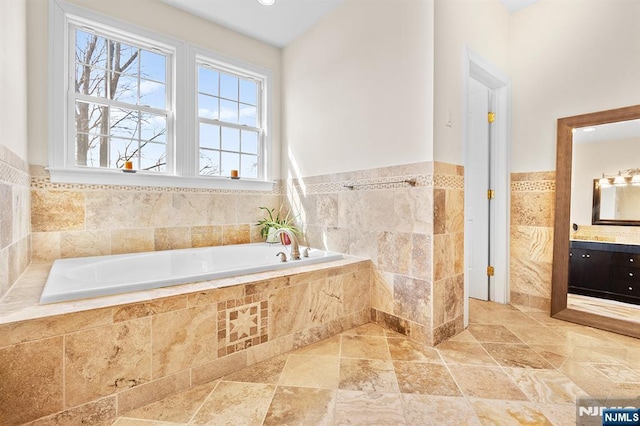 bathroom with vanity, a garden tub, and wainscoting