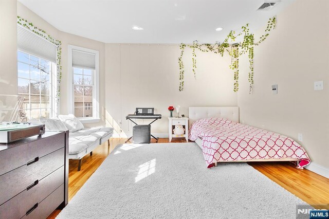 bedroom with recessed lighting, visible vents, baseboards, and wood finished floors