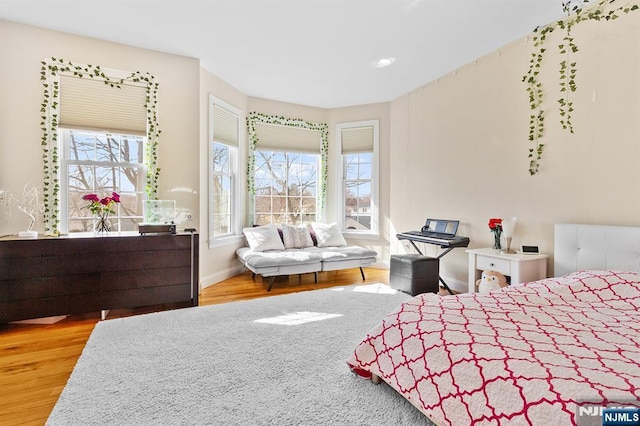 bedroom featuring multiple windows, baseboards, and wood finished floors