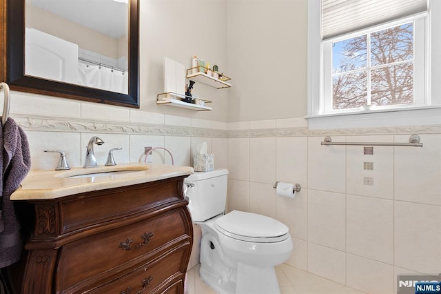 full bath featuring a wainscoted wall, toilet, tile walls, and vanity