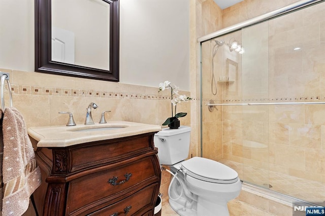 bathroom featuring toilet, tile walls, a stall shower, and vanity