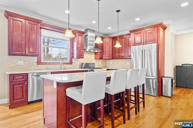 kitchen featuring dark brown cabinets, appliances with stainless steel finishes, wall chimney exhaust hood, and a sink