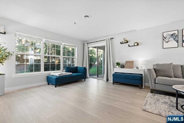 living area featuring wood finished floors, visible vents, and baseboards